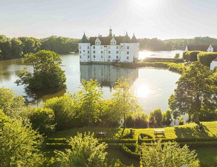 Wasserschloss Glücksburg mit Bäumen und Sonnenlicht
