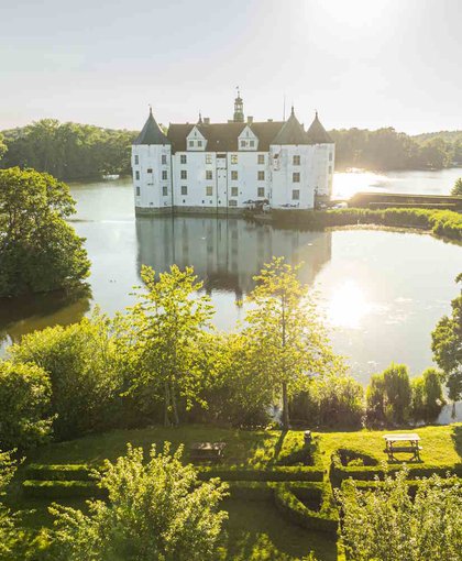 Wasserschloss Glücksburg mit Bäumen und Sonnenlicht