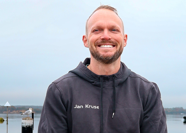Halbporträt Fitnesstrainer Jan Kruse, lächelnd vorder Kulisse der Ostsee in Glücksburg im Winter 