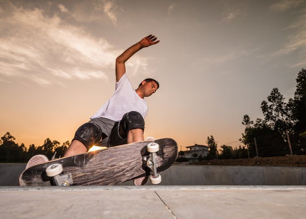 Junger Mann mit Skateboard beim Skaten auf einer Rampe