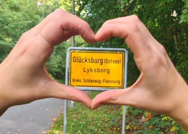 Hände formen Herz um Ortsschild