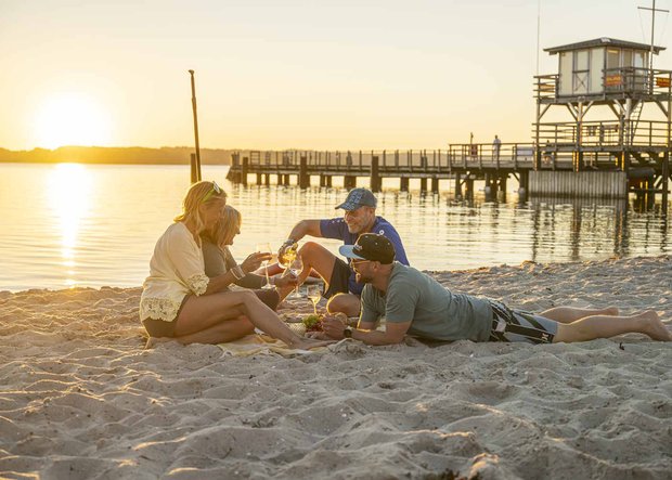 Familie sitzt im Sonnenuntergang am Strand Sandwig