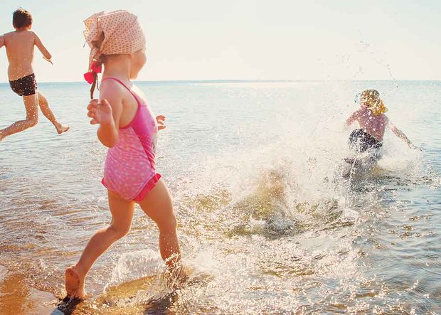 Kinder rennen ins Meer zum Baden 